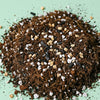 Heap of potting soil soil balanced and designed for calathea with coco coir, vermiculite, activated charcoal and perlite stones on a light green background
