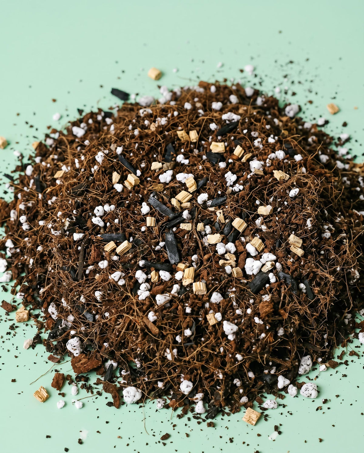 Heap of potting soil soil balanced and designed for calathea with coco coir, vermiculite, activated charcoal and perlite stones on a light green background