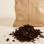 French bark for healthy plants on a white surface with a brown paper bag in the background.