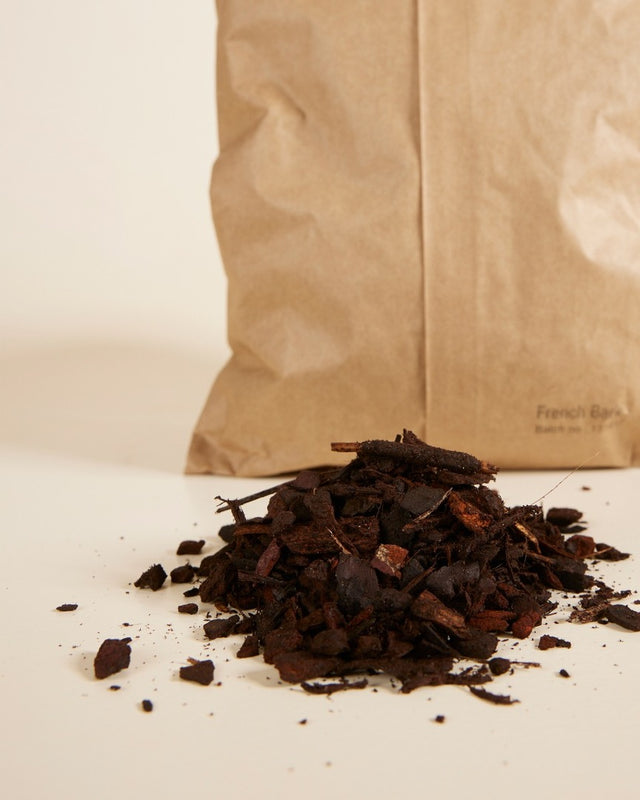 French bark for healthy plants on a white surface with a brown paper bag in the background.