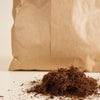 Brown paper bag with a pile of coco fibre material on a light background