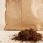 Brown paper bag with a pile of coco fibre material on a light background