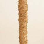 close up of a coco coir plant support pole on a beige backrgound