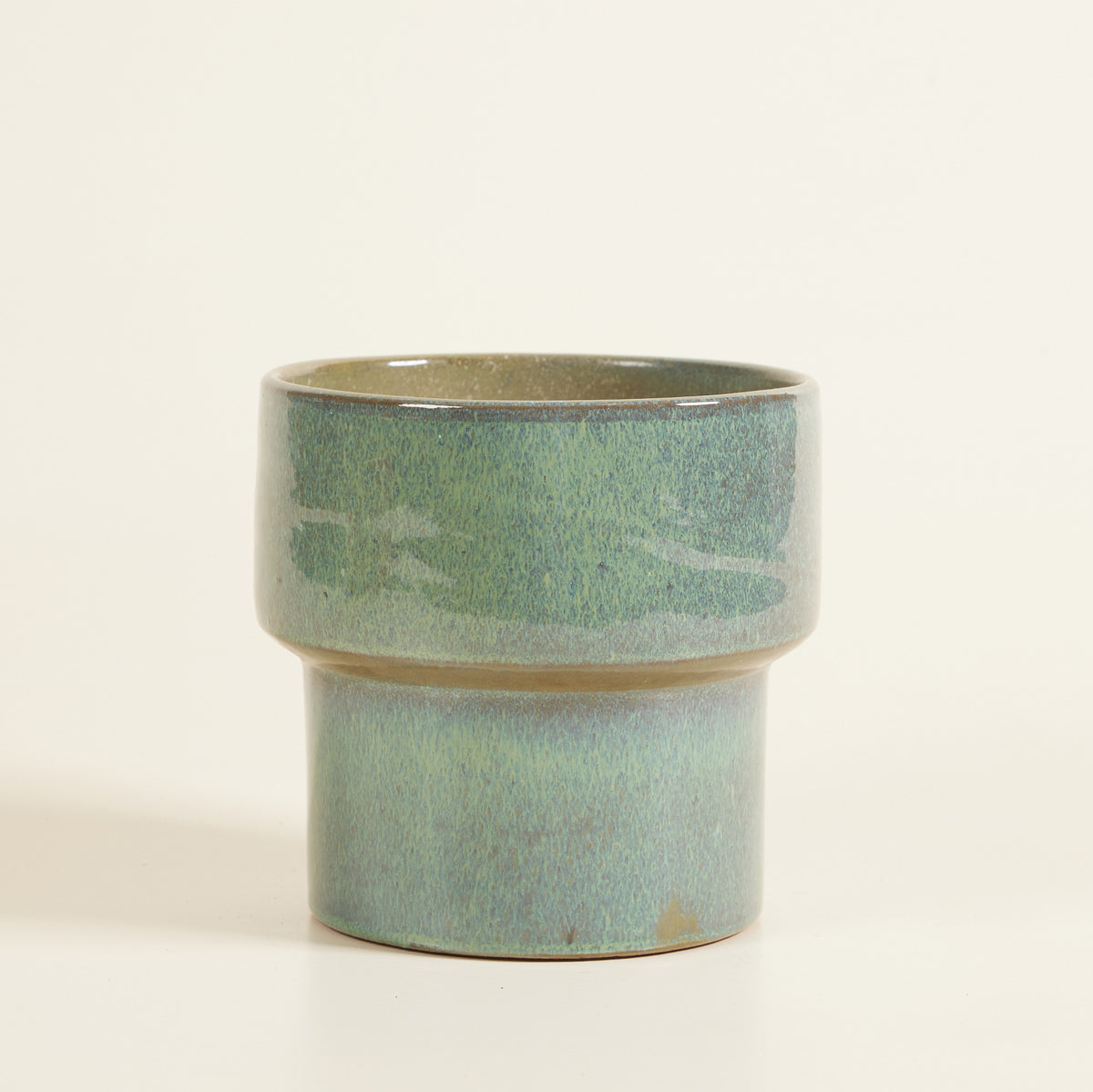 Ceramic planter with a green and beige glaze on a white background