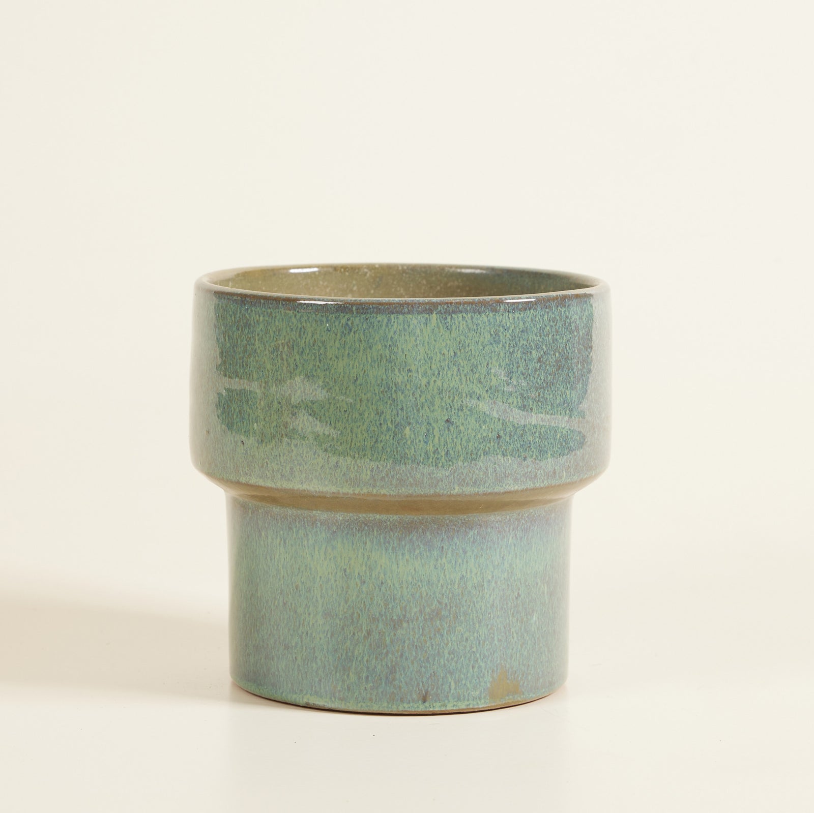 Ceramic planter with a green and beige glaze on a white background