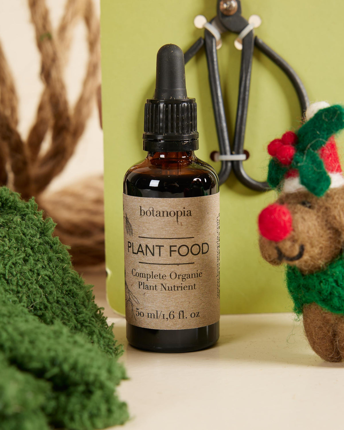 Bottle of botanopia plant food with a decorative plant and toy in the background