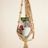 Macrame hammock with a felt toy and 'Rainbow Moon' packaging on a beige background