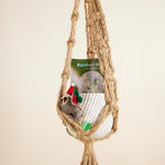 Macrame hammock with a felt toy and 'Rainbow Moon' packaging on a beige background