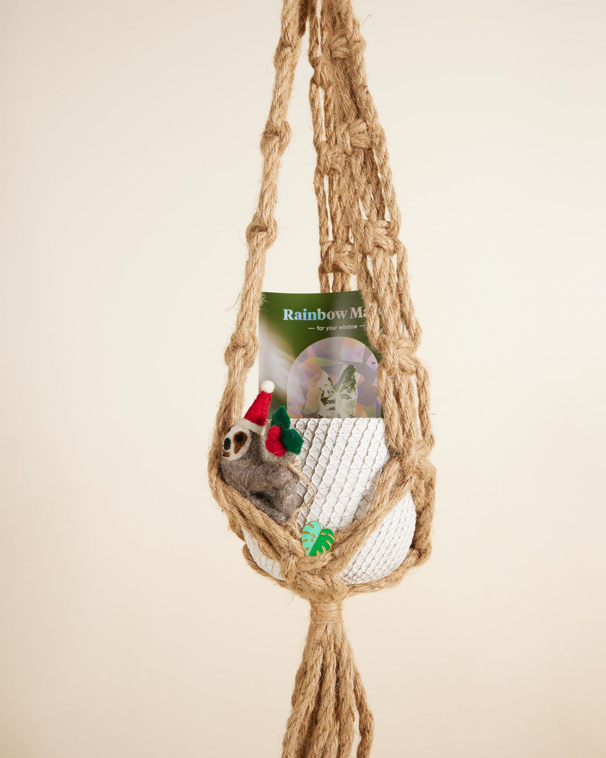 Macrame hammock with a felt toy and 'Rainbow Moon' packaging on a beige background