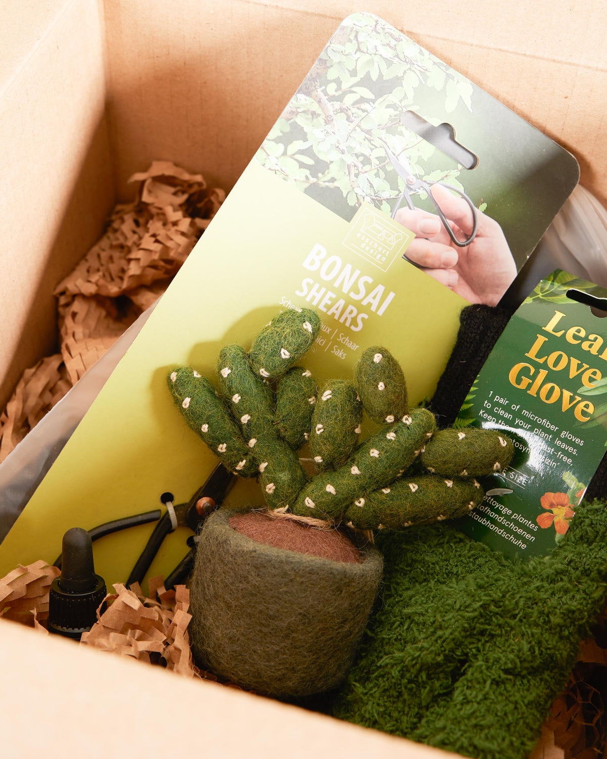 Small felt plant toy with bonsai shears and a leaf love glove in a box.