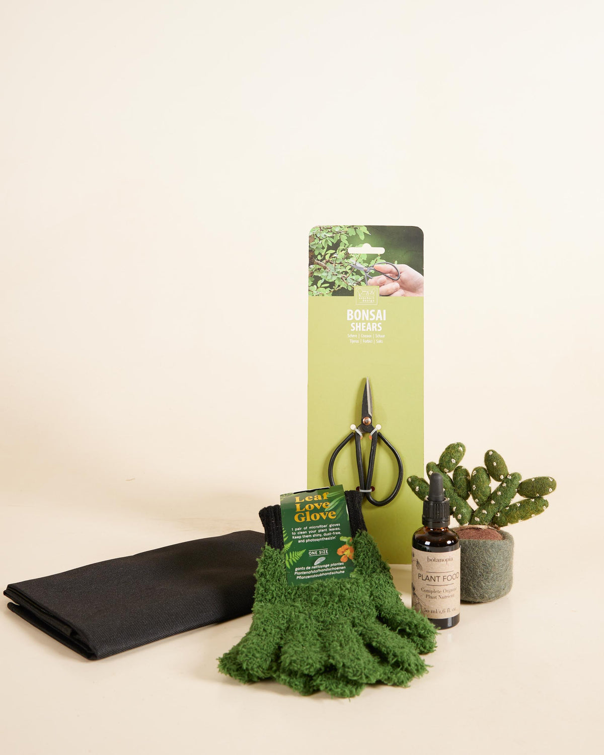 Gardening tools and supplies including a pair of shears, gloves, and a plant pot on a beige background.