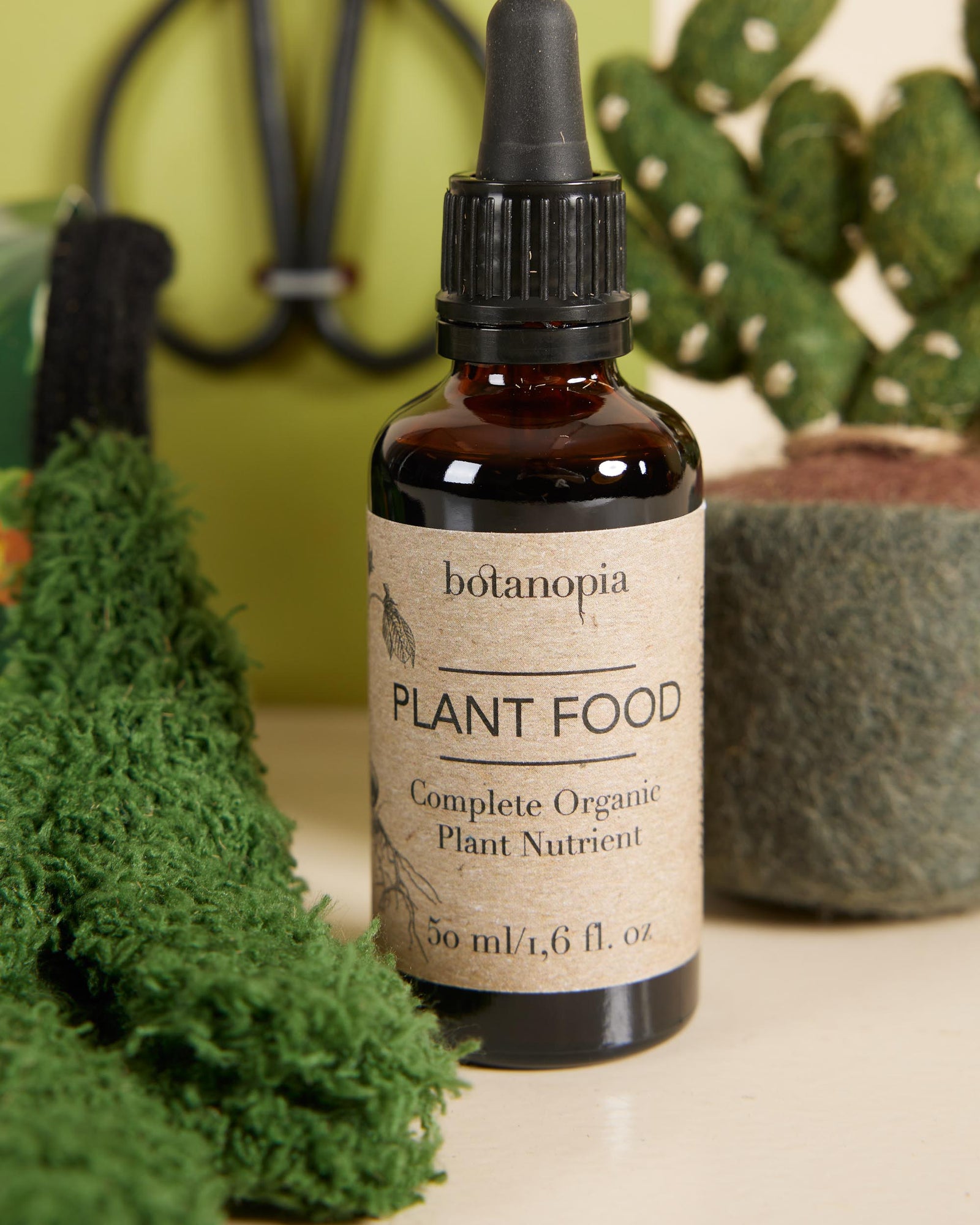 Bottle of botanopia plant food with plants in the background
