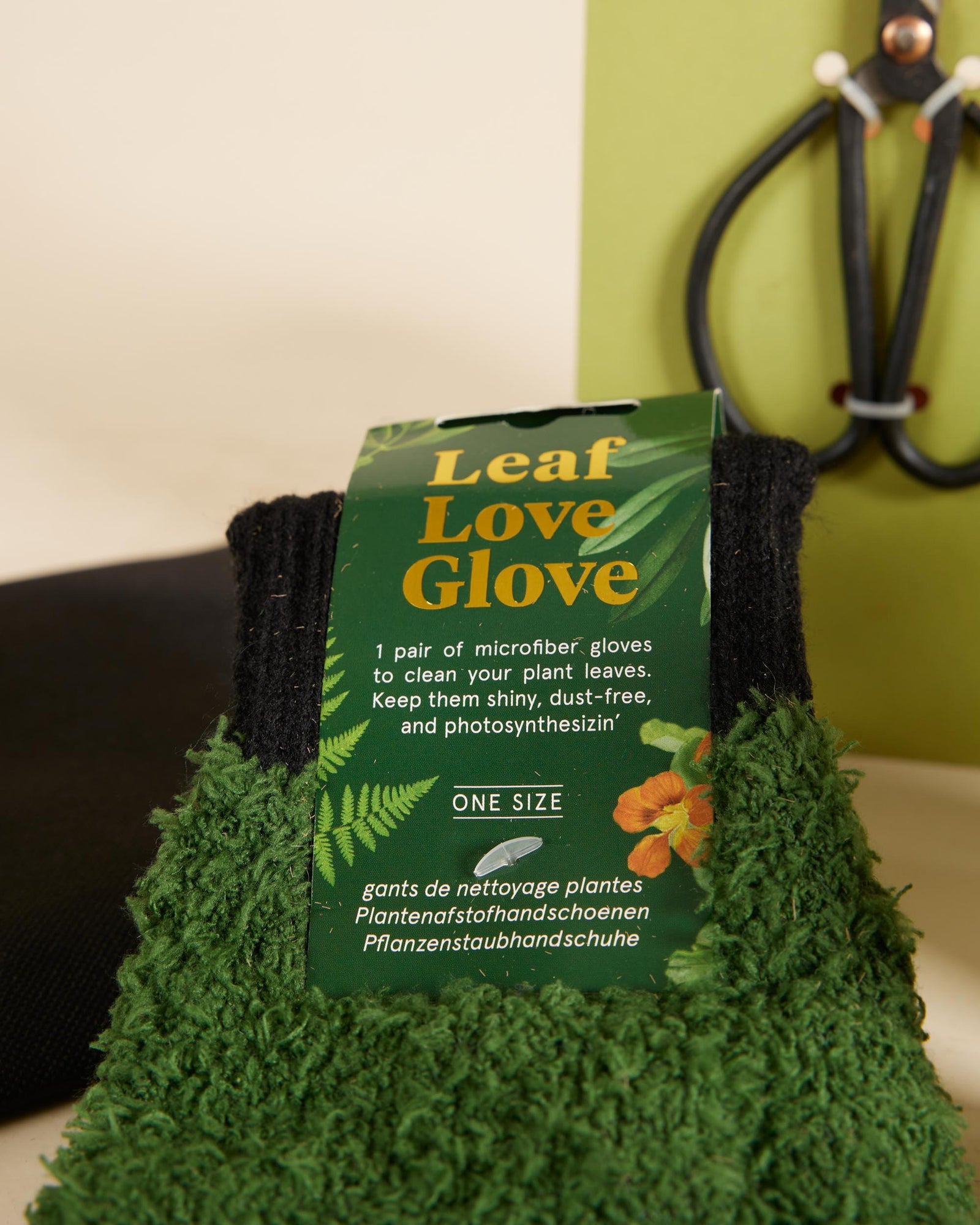 Green gloves with 'Leaf Love Glove' packaging on a plant